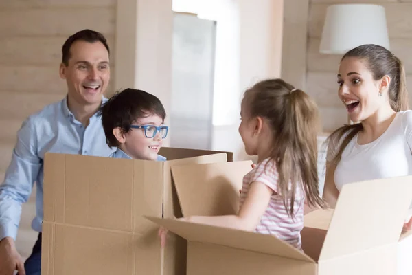 Les petits enfants sautent des boîtes en carton en jouant avec les parents — Photo