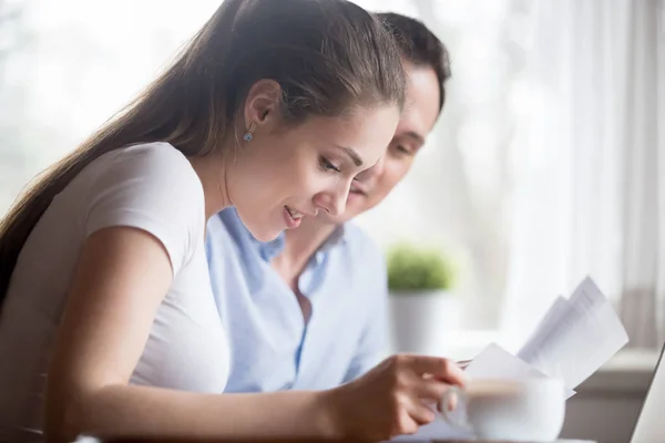 Close up of happy couple reading good news on documents