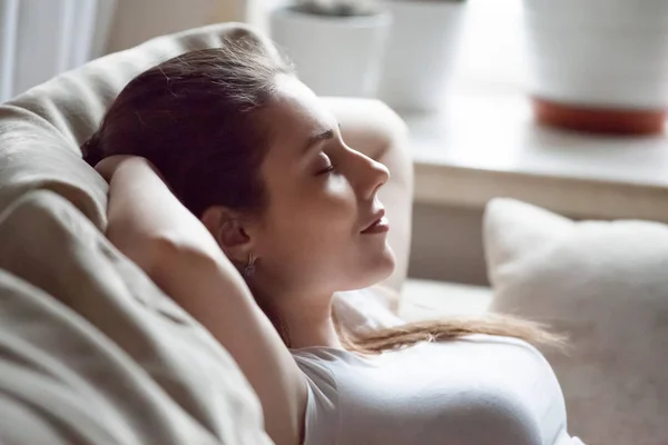 Calm woman relaxing on sofa hands over head — Stock Photo, Image