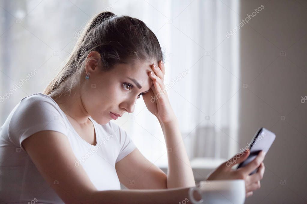 Upset young woman disappointed getting bad message on smartphone