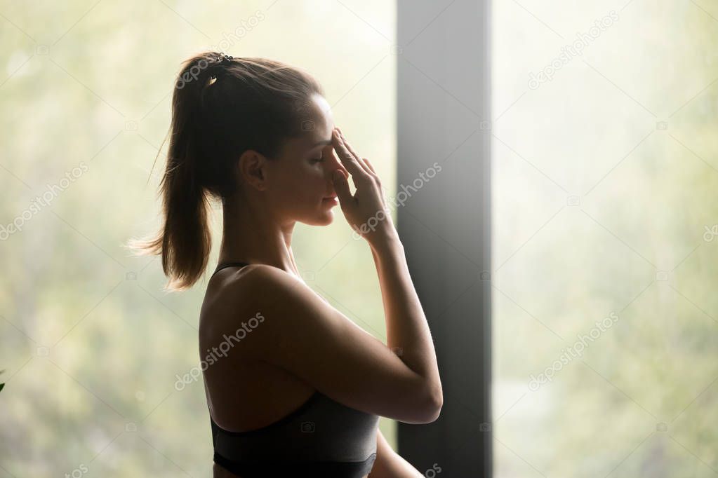 Young sporty woman doing Alternate Nostril Breathing