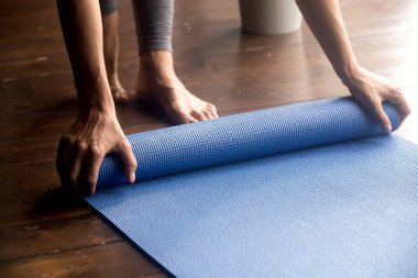 Uygulama, kadın için zaman unrolling mavi yoga mat eller