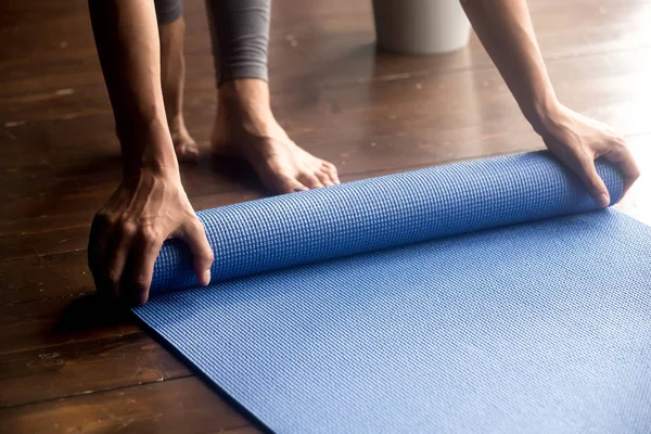 Tempo para a prática, mãos femininas unrolling tapete de ioga azul — Fotografia de Stock