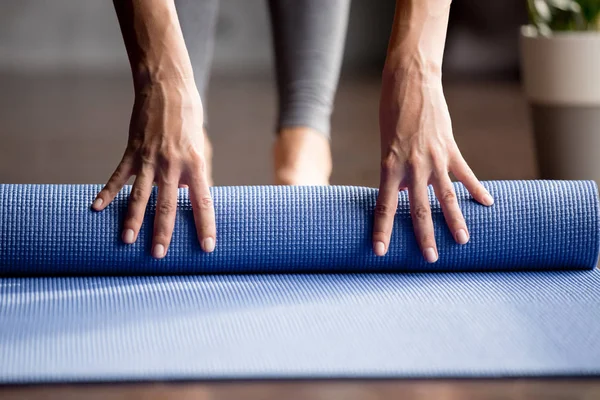 Mão meninas dobrável tapete de exercício azul no chão — Fotografia de Stock