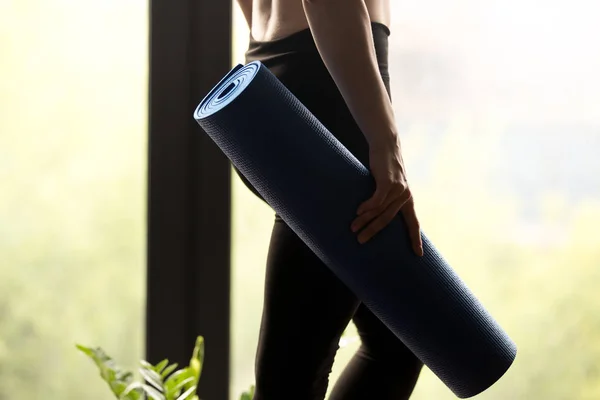 Deportiva mujer sosteniendo estera de yoga, de cerca —  Fotos de Stock