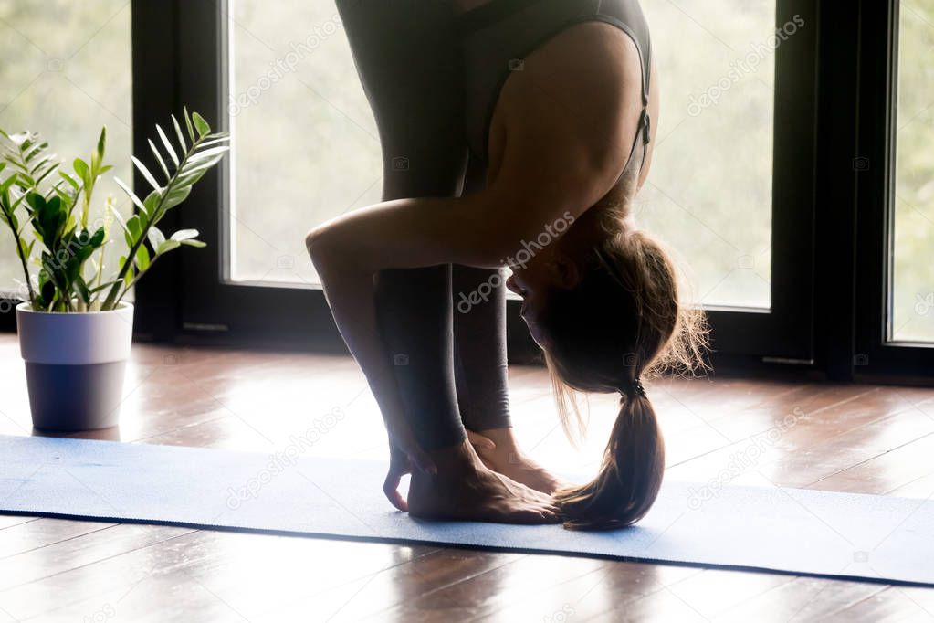 Sporty yogi woman doing uttanasana pose, close up view