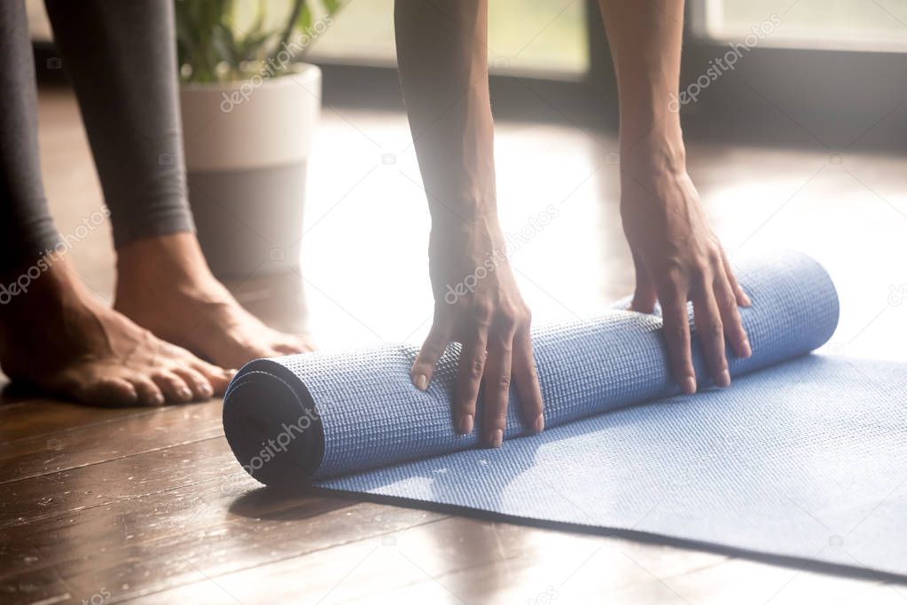 Woman unrolling blue yoga mat, legs close up