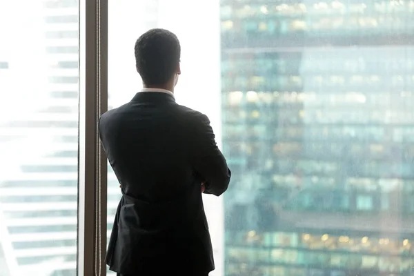 Erfolgreicher nachdenklicher Geschäftsmann, der durch das Fenster auf — Stockfoto