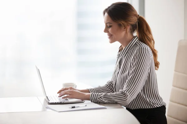 Happy businesswoman texting at laptop distracted from work — Stock Photo, Image