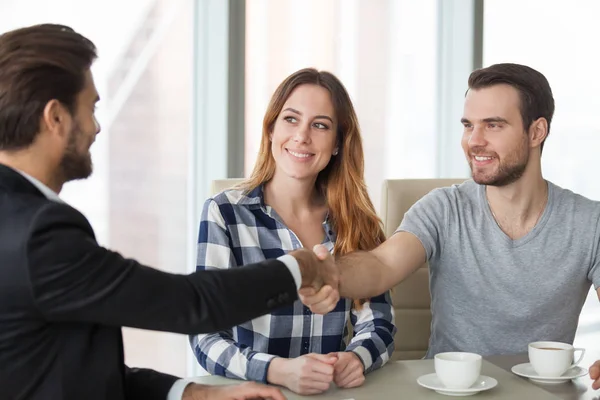 Gelukkige paar handshaking consulting agent bezoeken hem op kantoor — Stockfoto