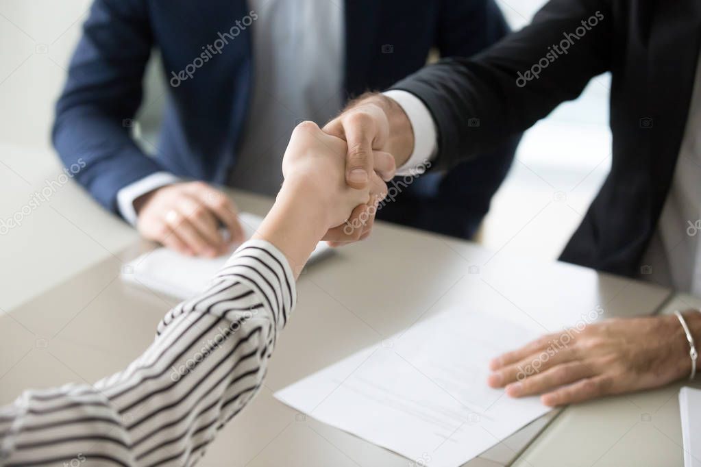 Close up of HR handshaking female job applicant at interview