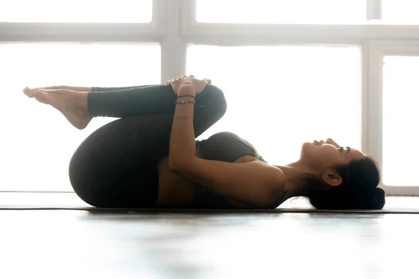 Young sporty woman practicing yoga, doing Knees to Chest exercis — Stock Photo, Image