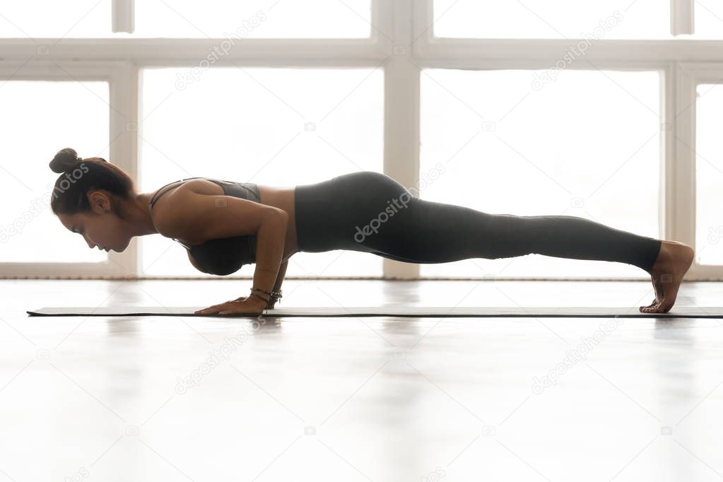 Young attractive woman practicing yoga, doing four limbed staff 