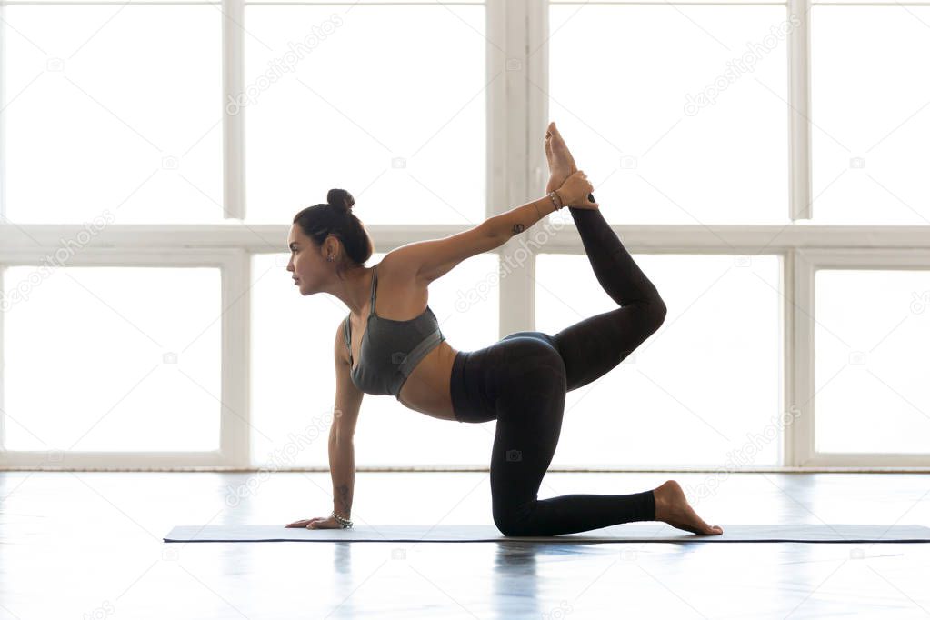 Young sporty attractive woman practicing yoga, doing tiger exerc
