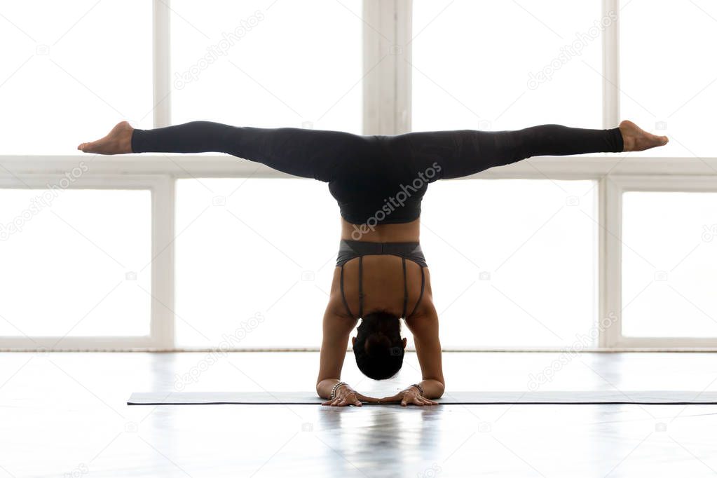 Young woman practicing yoga, doing Pincha Mayurasana exercise, r
