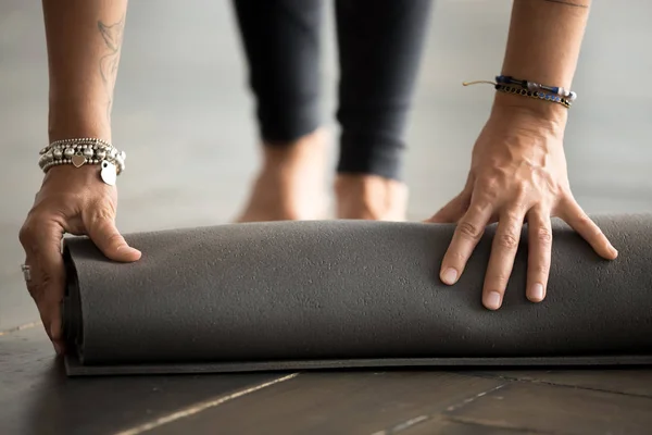 Fit meisjes hand opvouwbare zwarte oefening mat op de vloer — Stockfoto