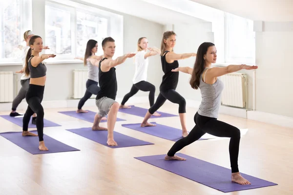 Grupp av sportiga människor som utövar yoga med instruktör, Warrior — Stockfoto