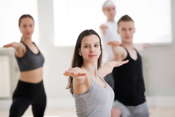 Группа спортивных людей, практикующих йогу, поза Воина-2 — стоковое фото