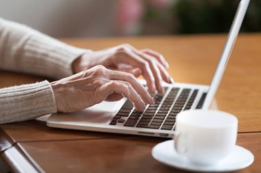 Metin yazarak klavye, laptop çalışan üst düzey yaşlı iş kadın, online, iletişim e-posta, yazarken bilgisayar kavramı kullanarak eski veya orta yaşlı kadın Olgun eller görünümünü kapat