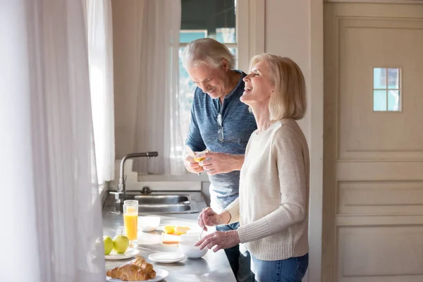 Feliz pareja de ancianos divirtiéndose preparando el desayuno en el kitche — Foto de Stock