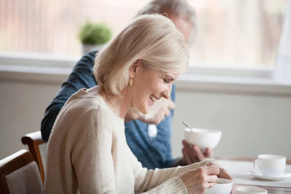 Счастливая пожилая женщина завтракает с пожилым мужем дома — стоковое фото