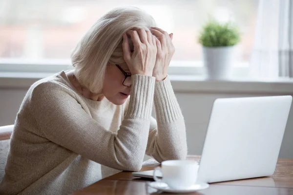 Femme d'âge moyen devant un ordinateur portable frustré par les mauvaises nouvelles — Photo