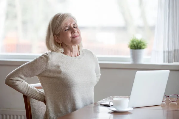 Aufgeregt ältere Frau sitzt Gefühl Rückenschmerzen massieren schmerzende Muskeln — Stockfoto