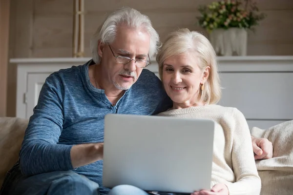 Rentnerehepaar mit Laptop im Gespräch auf Sofa — Stockfoto