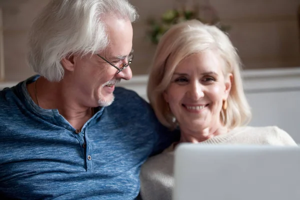 Liebevolle Senior Ehemann Blick auf lächelnde ältere Frau mit Lapto — Stockfoto