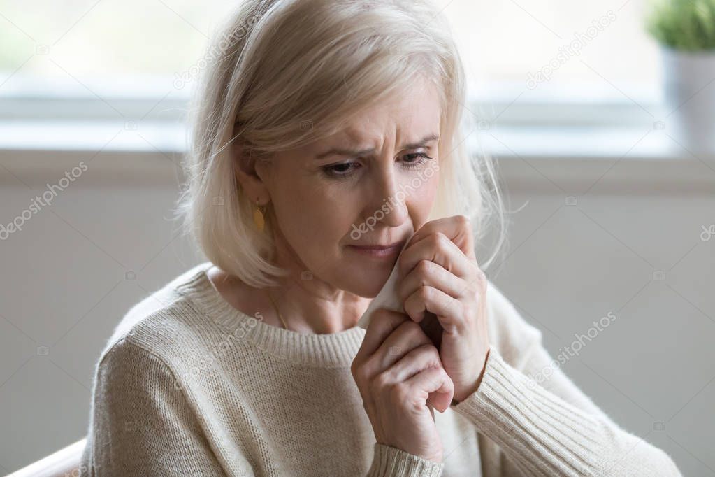 Upset middle aged woman wiping tears crying feeling depressed lo