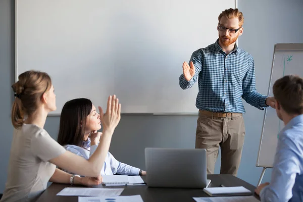 Businesswoman raising hand up at meeting asking team leader ques