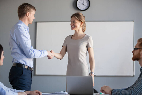 Smiling businesswoman shaking hand welcoming male business partn