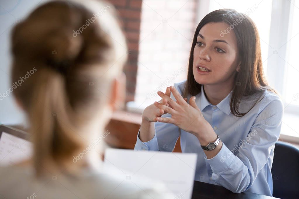 Confident focused businesswoman speaking to people at business n