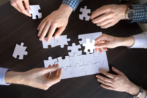 Top close up view of hands engaged in assembling puzzle — Stock Photo, Image