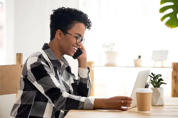 Femme souriante travaillant à l'aide d'un ordinateur et d'un téléphone au bureau — Photo