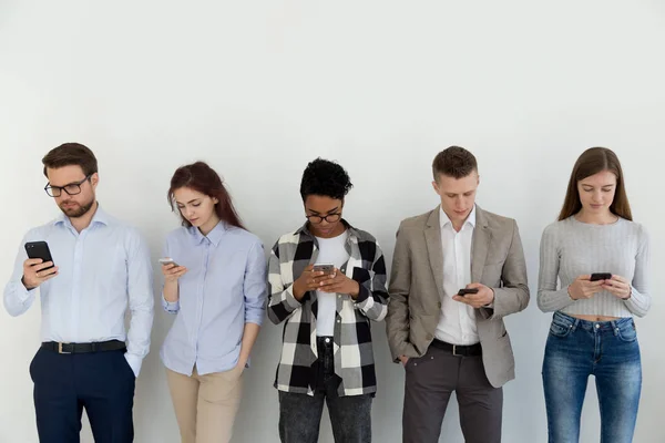 Grupo de estudiantes usando teléfonos inteligentes de pie en interiores — Foto de Stock