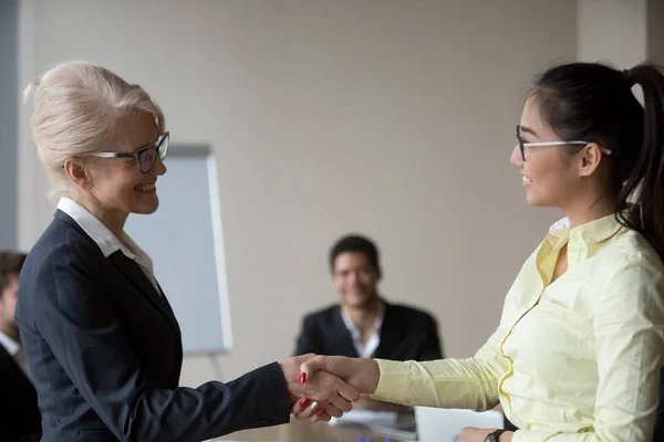 Female boss handshaking Asian employee congratulating with promo — Stock Photo, Image