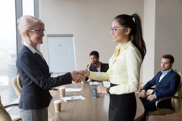 Smiling businesswoman handshake Asian employee greeting with ach — Stock Photo, Image