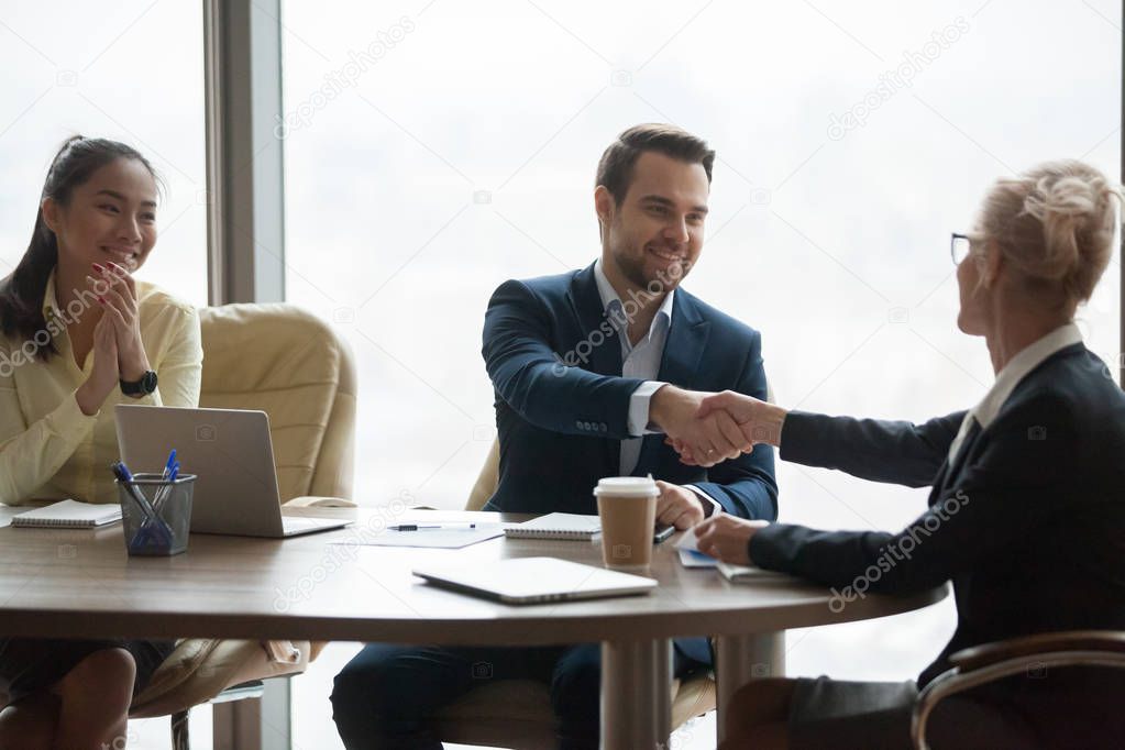 Female boos handshaking partner closing deal at meeting