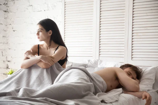 Sad woman and sleeping man lying in bed — Stock Photo, Image