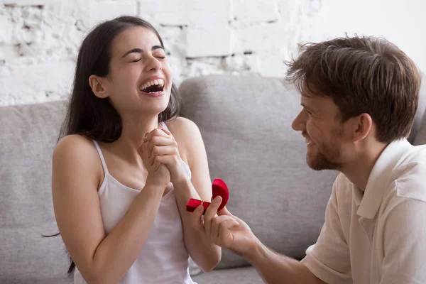 Счастливый молодой человек делает предложение своей девушке, сидящей на диване — стоковое фото