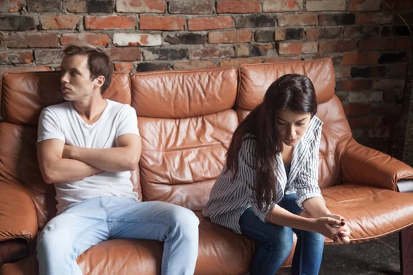 Unhappy young man and woman in quarrel sitting on couch — Stock Photo, Image