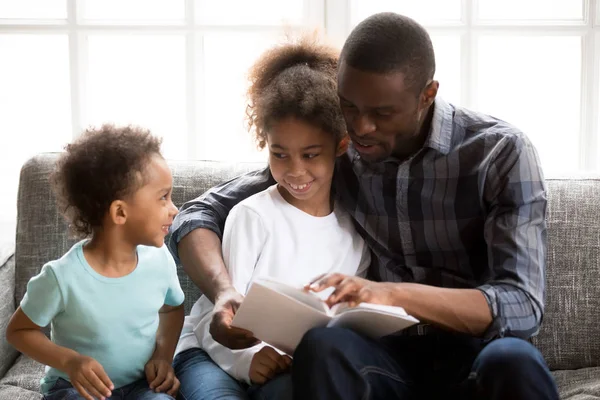 Père avec enfants lire un livre à la maison — Photo