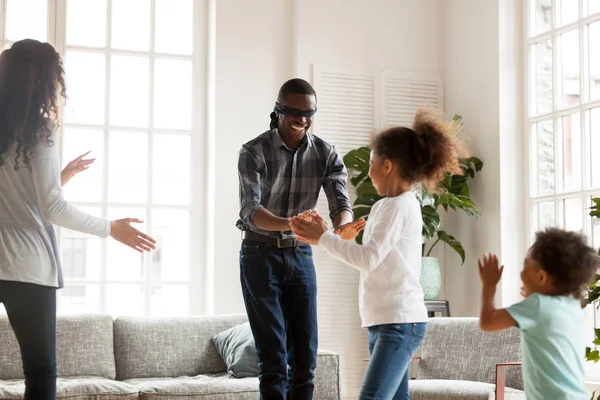 Black family playing hide and seek in living room — Stock Photo, Image