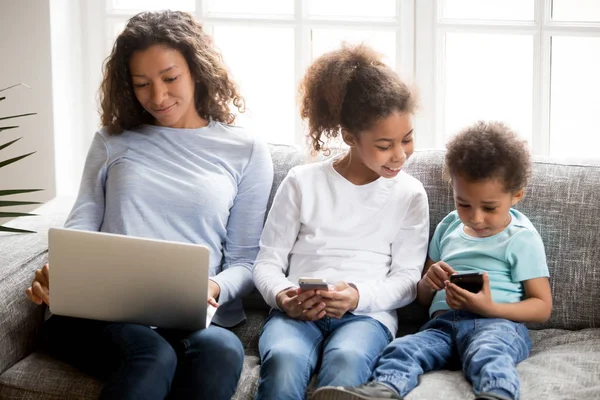 Madre y dos niños junto con gadgets en el sofá —  Fotos de Stock