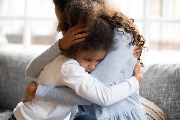 Black mother and daughter embracing sitting on couch — Stock Photo, Image