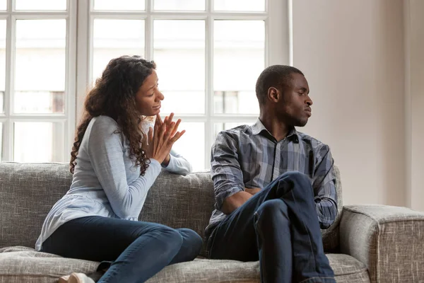 Angry husband and guilty wife sitting on couch at home — Stock Photo, Image