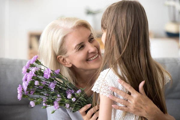 Babcia szczęśliwy uścisk małych wnuczka dziękując za kwiaty — Zdjęcie stockowe