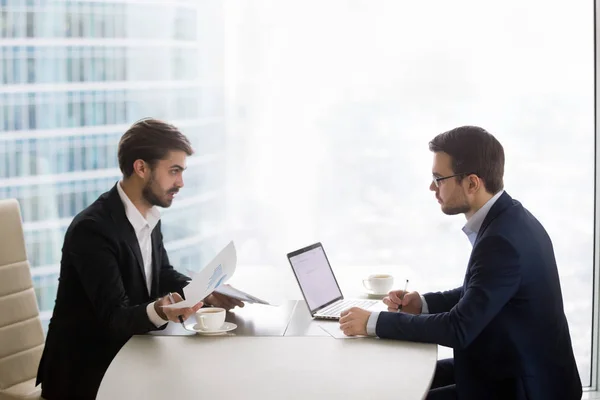 Два чоловіки розмовляють і працюють з паперами в офісі — стокове фото