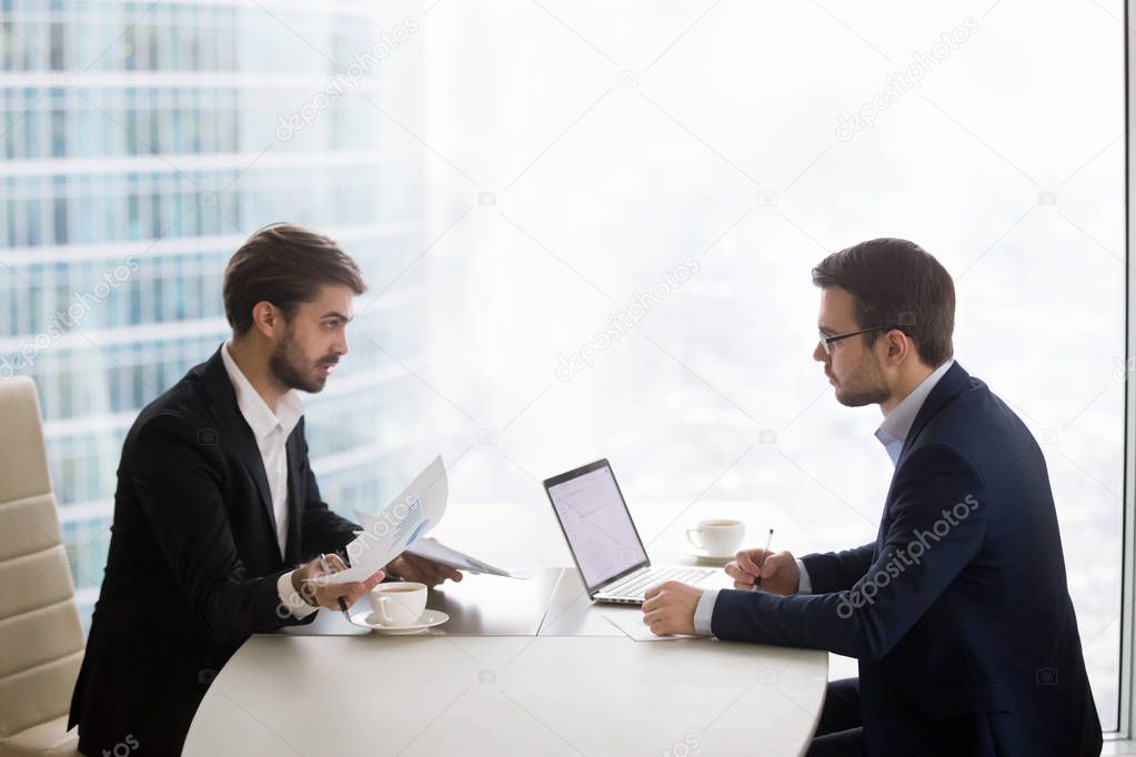 Two men are talking and working with papers in office